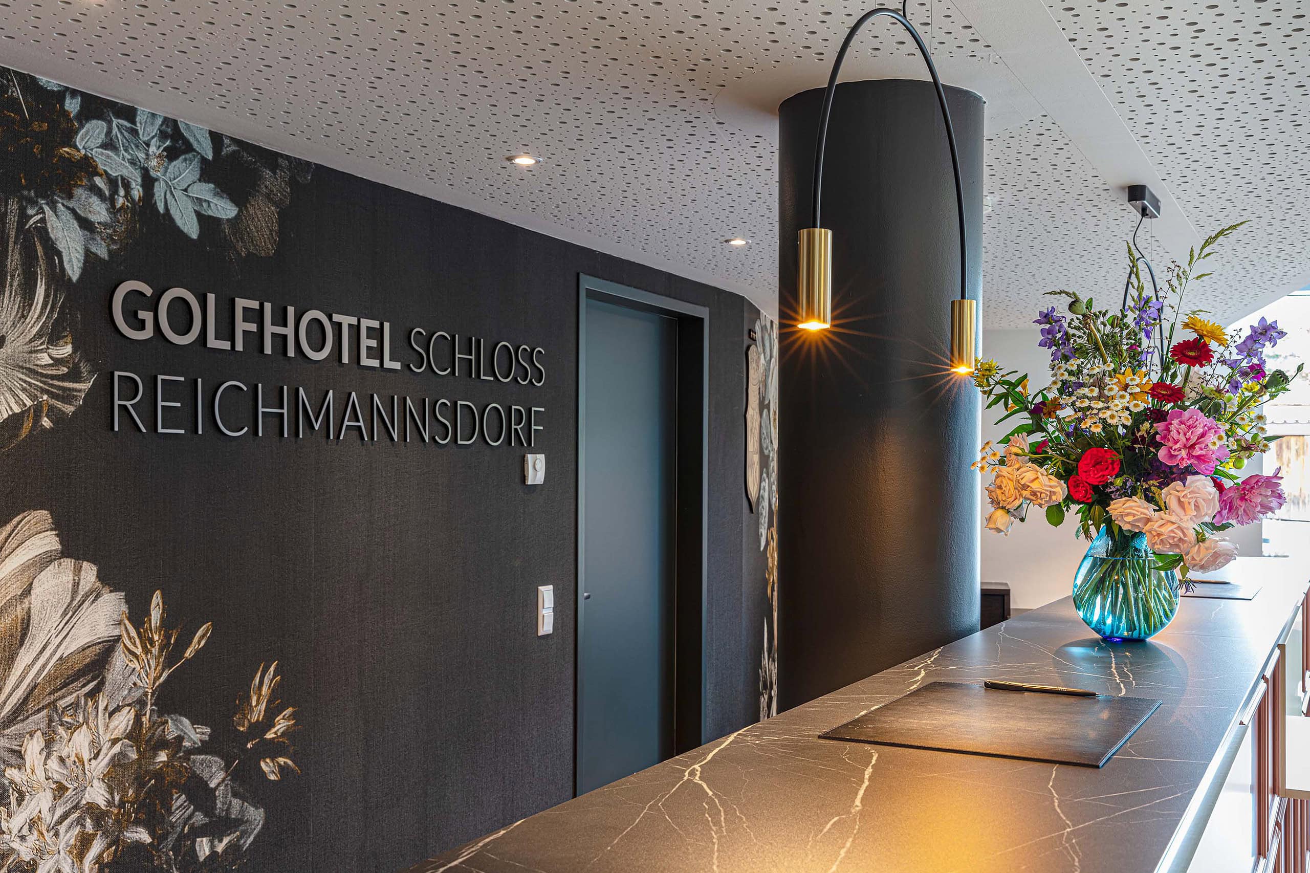 Empfangstresen mit Schriftzug Golfhotel Schloss Reichmannsdorf und Blumenstrauß