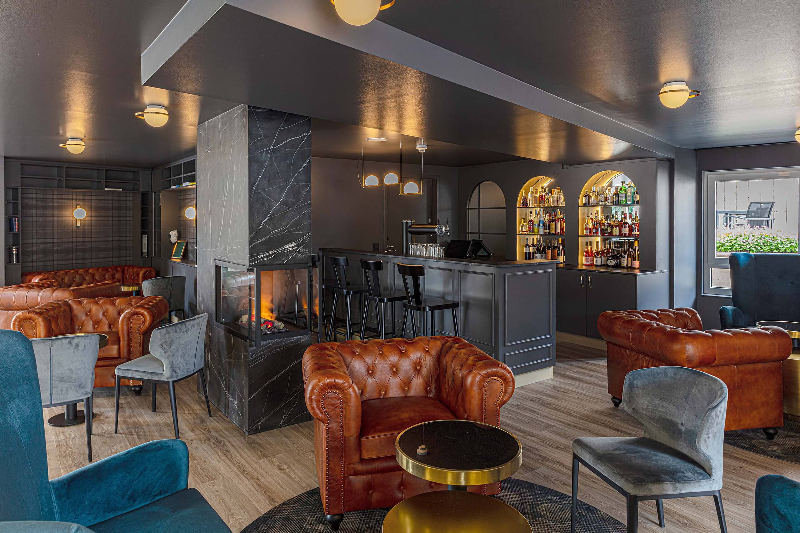 Hotelbar mit Kamin, Chesterfield-Sesseln und Barhockern in Blau und Cognac