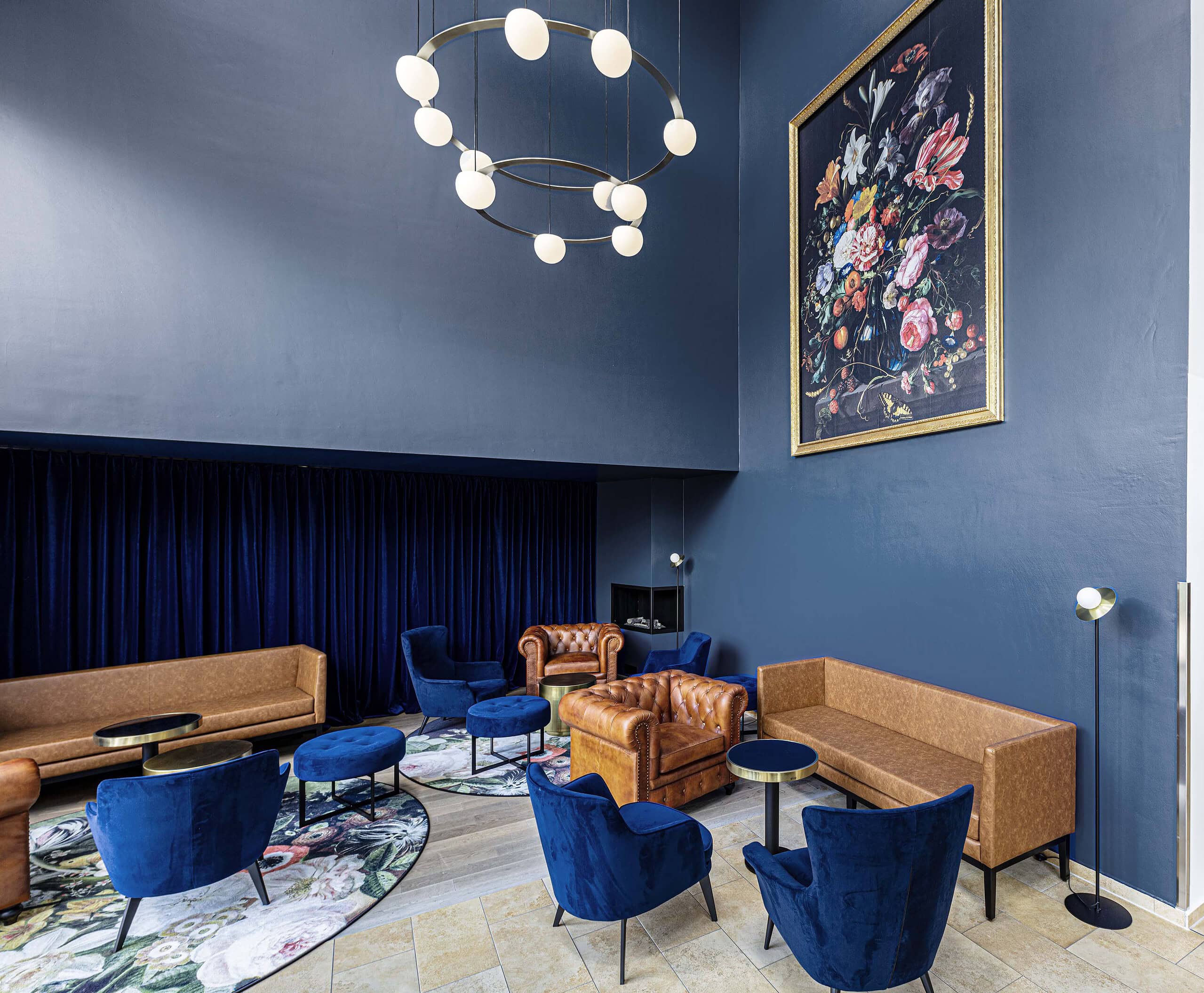 Zweigeschossige Lounge mit dunkelblauer Wand, Blumengemälde und Ledersofas