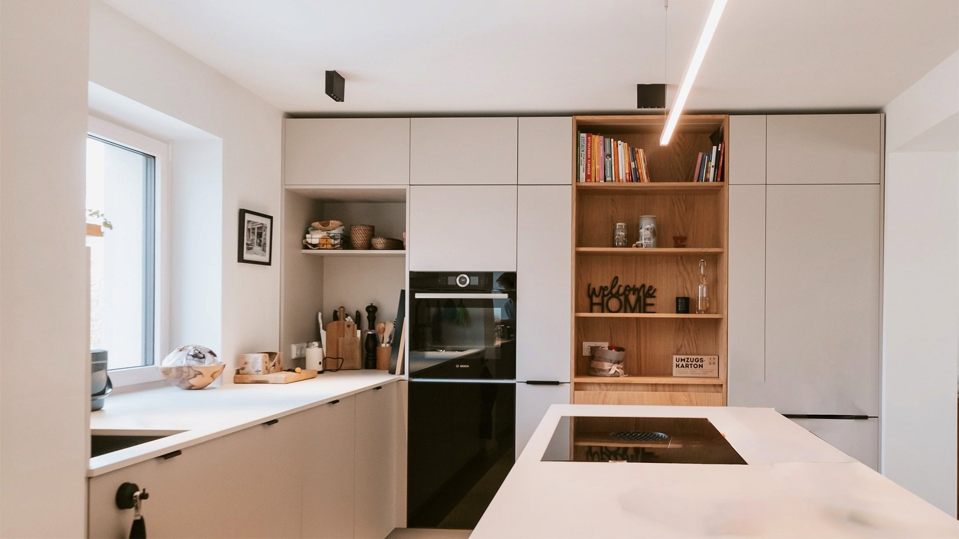 Innenarchitektur München, Büro Innenarchitektur Federleicht – Moderne Küche mit integrierter Kochinsel, offenen Regalen und warmen Holzakzenten