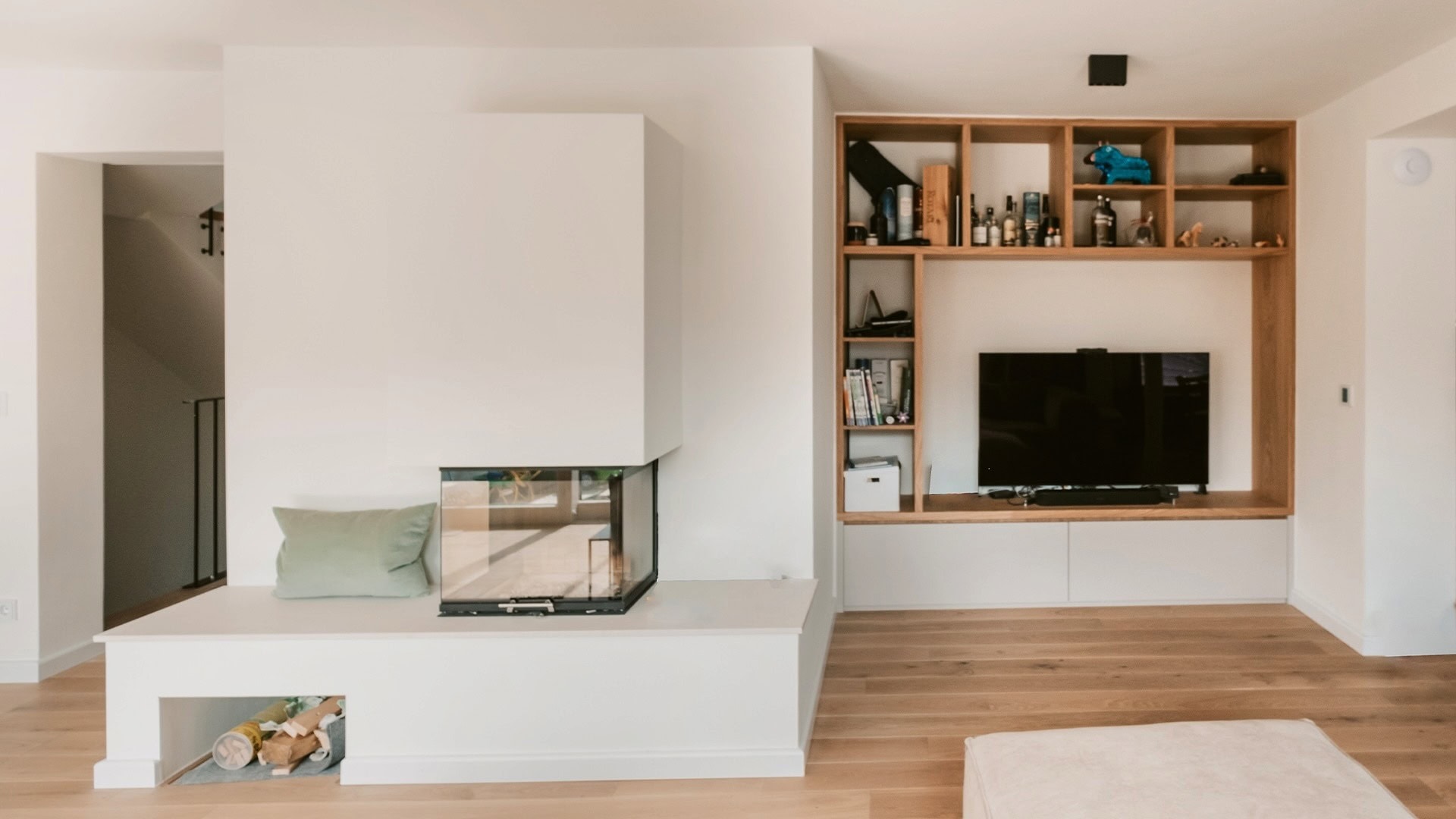 Innenarchitektur München, Büro Innenarchitektur Federleicht – Moderner Wohnbereich mit integriertem Kamin, maßgefertigtem Regal und gemütlichem Sitzbereich
