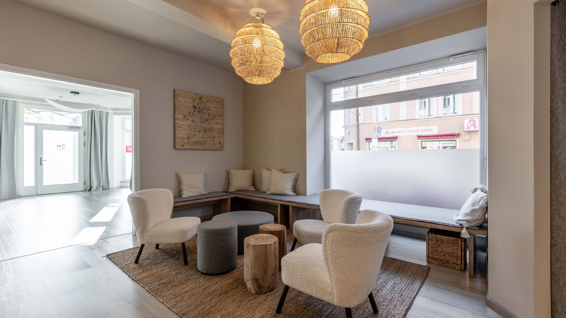 Innenarchitektur München / Innenarchitektur Federleicht - Lounge-Bereich im Yogastudio mit Holzmöbeln, weichen Stoffhockern und natürlicher Gestaltung