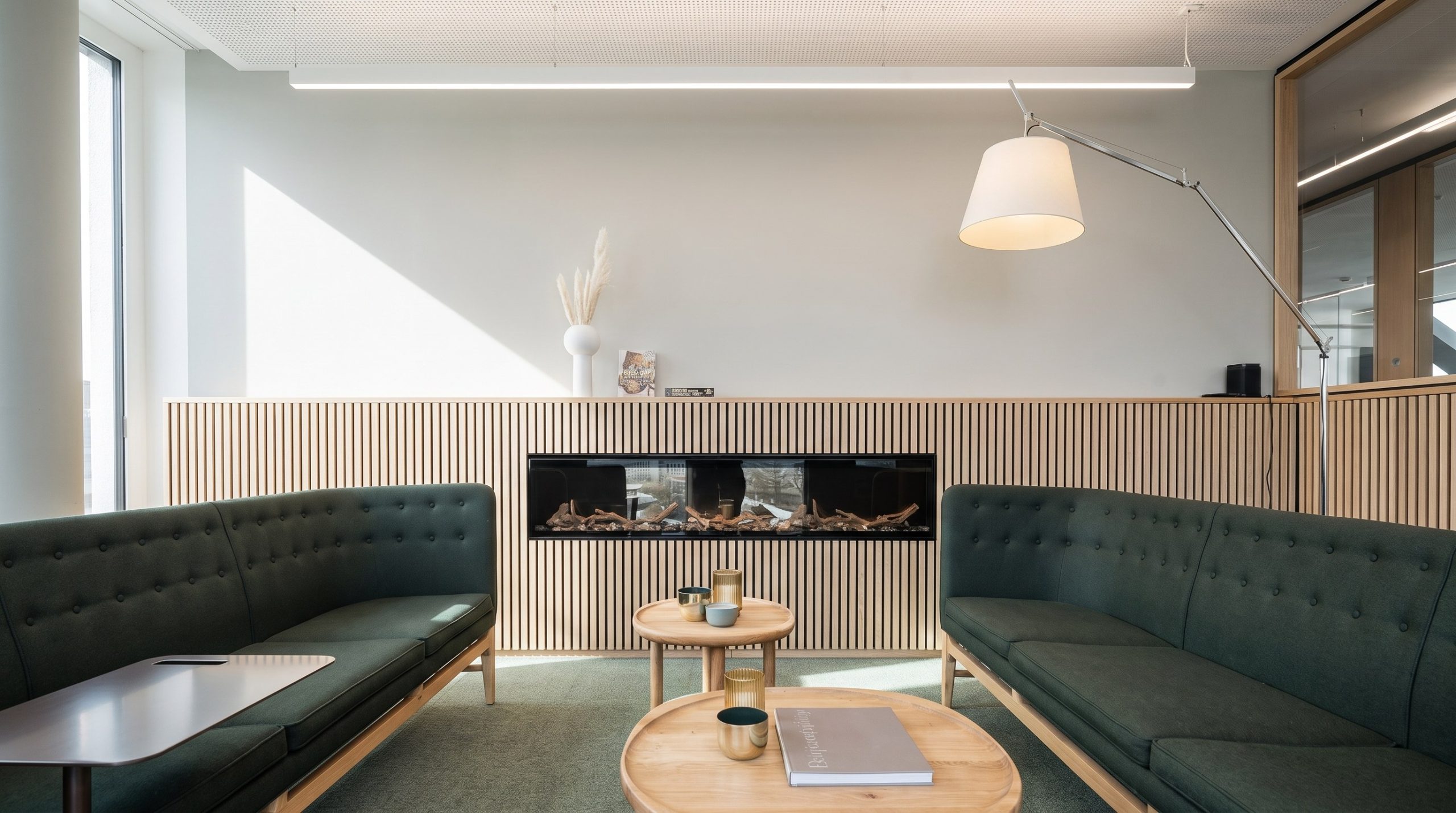Kaminlounge mit grünen Sofas und Holzlamellenwand bei Tengelmann Twenty-One KG in München, Innenarchitektur Federleicht