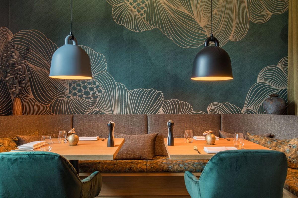 Innenarchitektur München / Innenarchitektur Federleicht - Stilvolle Sitznische im Speisesaal des La Soa Chalets mit petrolfarbener Wandgestaltung, Pendelleuchten und eleganten Polstermöbeln aus Samt