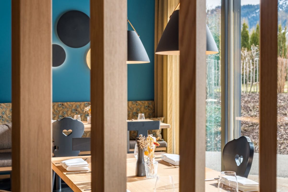 Innenarchitektur München / Innenarchitektur Federleicht - Detailaufnahme eines modernen Speisesaals mit Herzlehnen-Stühlen, Holzlamellen und stilvoller Beleuchtung