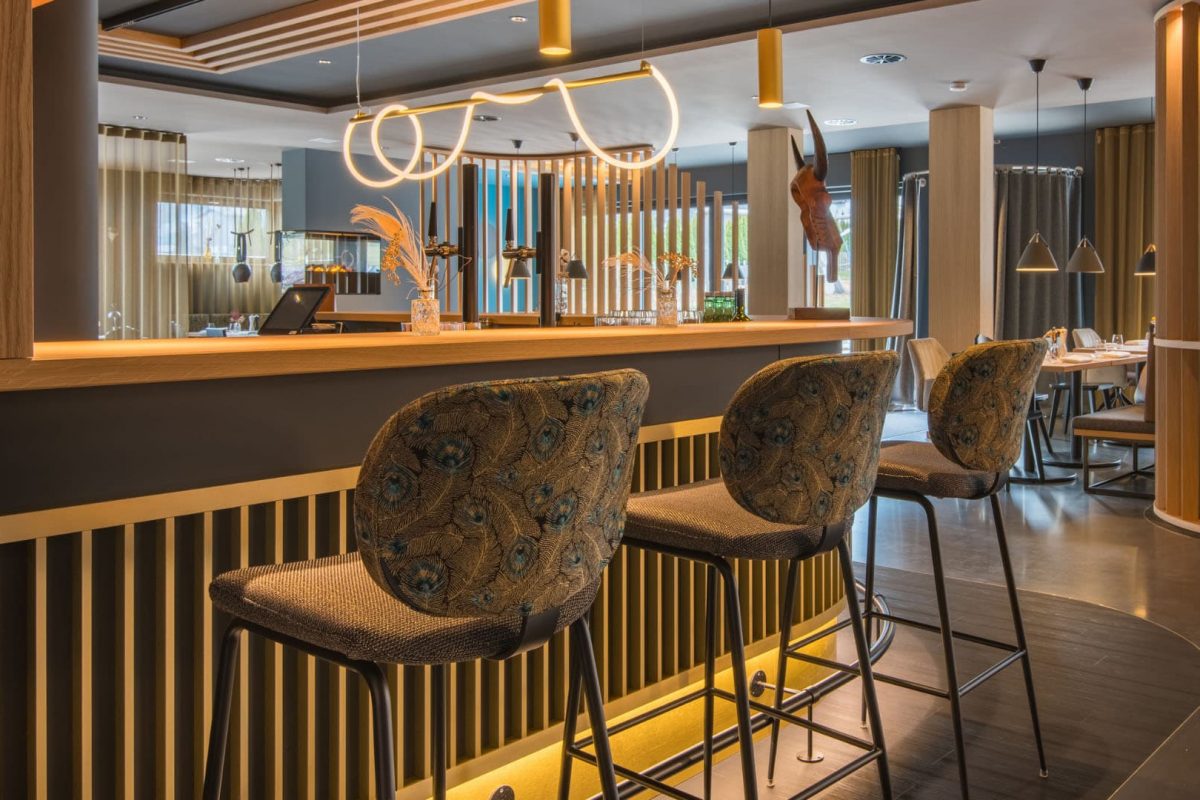 Innenarchitektur München / Innenarchitektur Federleicht - Moderner Barbereich La Soa Chalets mit Holz- und Messingdetails sowie stilvoller Beleuchtung und Barhockern