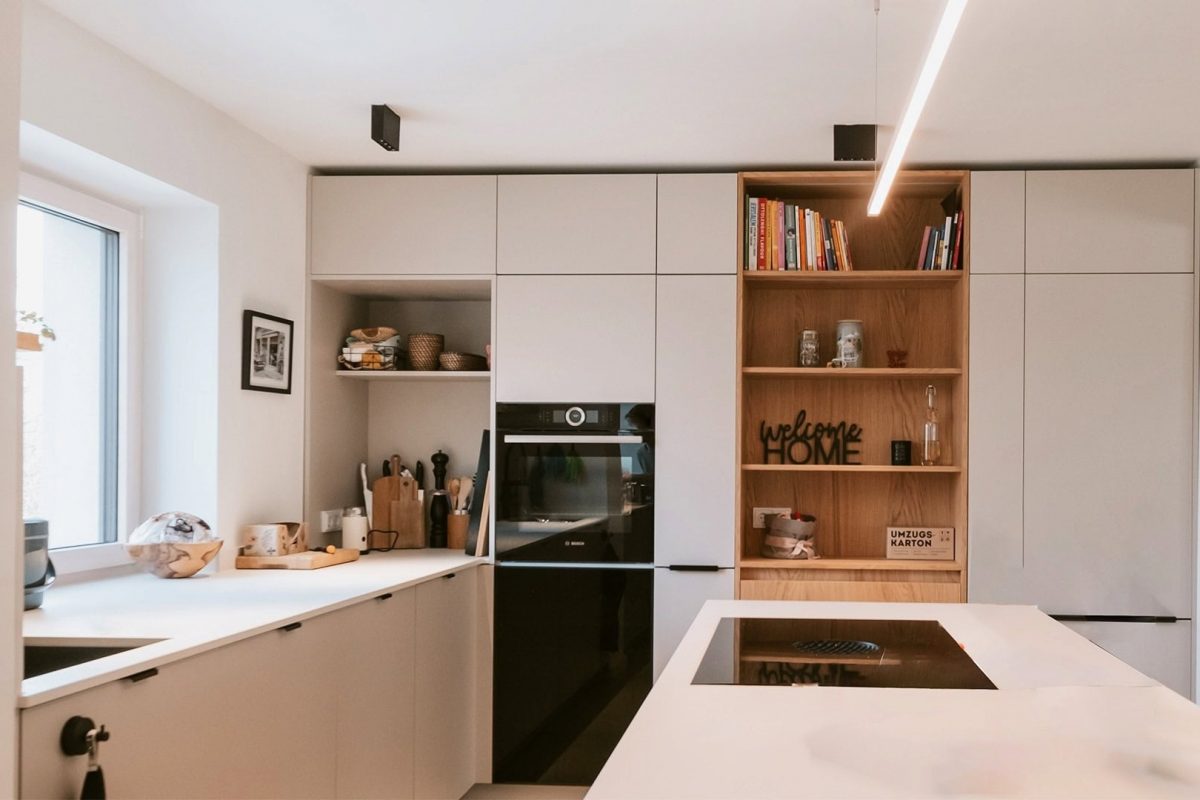 Innenarchitektur München, Büro Innenarchitektur Federleicht – Moderne Küche mit integrierter Kochinsel, offenen Regalen und warmen Holzakzenten