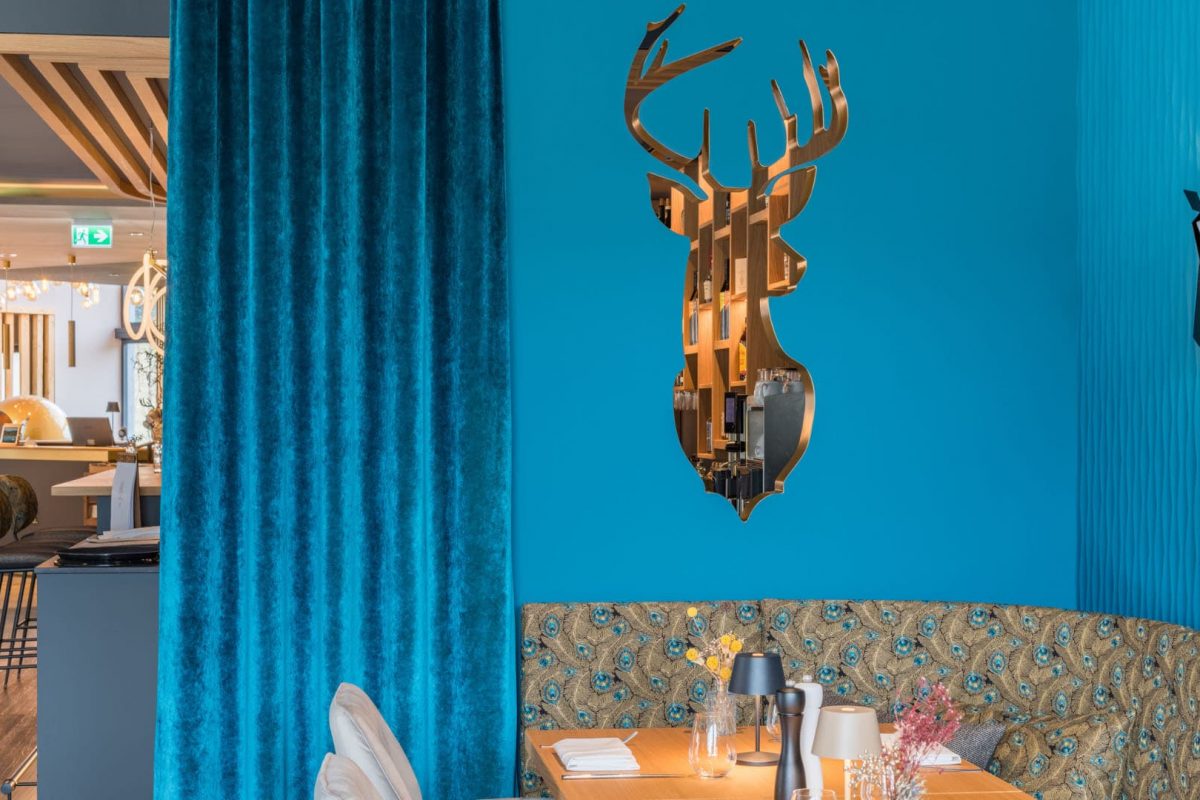 Innenarchitektur München / Innenarchitektur Federleicht - Wandgestaltung mit Loch in Form eines Hirschkopfs und Samtvorhängen im Speisesaal des La Soa Chalets