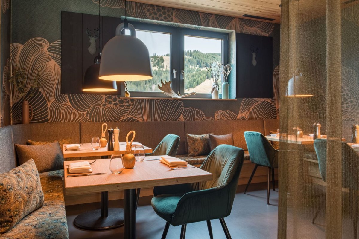 Innenarchitektur München / Innenarchitektur Federleicht - Gemütlicher Speisesaal im La Soa Chalets mit warmen Holztönen, Petrol-Akzenten und stimmiger Beleuchtung