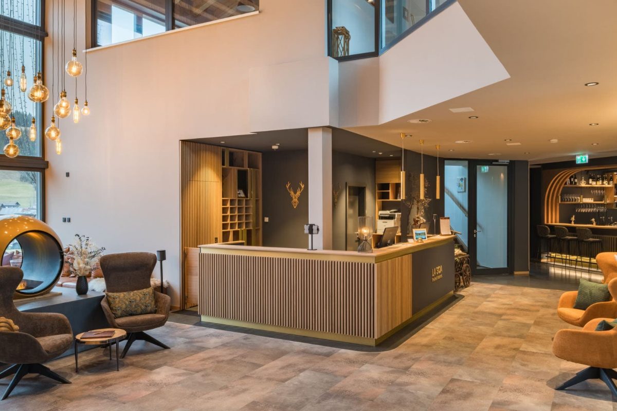 Innenarchitektur München / Innenarchitektur Federleicht - Empfangsbereich Neugestaltung La Soa Chalets mit Holzlamellen, Messingdetails und modernen Akzenten im alpinen Stil