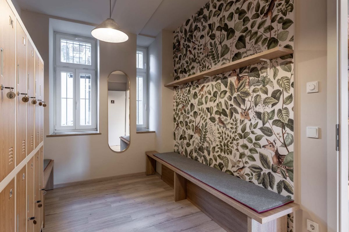 Innenarchitektur München / Innenarchitektur Federleicht - Damen-Umkleide im Yogastudio mit Waldtapete, Holzbank und schlichter Beleuchtung