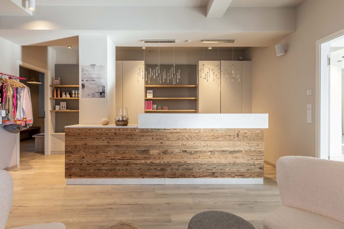 Innenarchitektur München / Innenarchitektur Federleicht - Empfangsbereich mit Holzdetails, minimalistischen Regalen und moderner Beleuchtung im Yogastudio