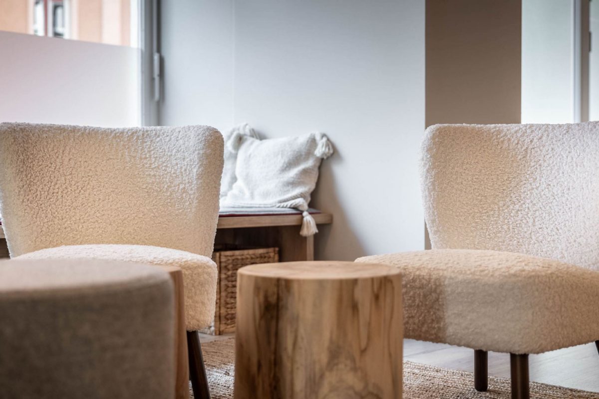 Innenarchitektur München / Innenarchitektur Federleicht - Detailaufnahme eines gemütlichen Empfangsbereichs mit Naturmaterialien, Holzdetails und weichen Stoffmöbeln