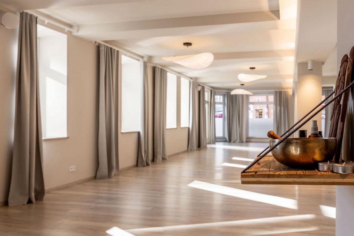 Innenarchitektur München / Innenarchitektur Federleicht - Lichtdurchfluteter Yogaraum mit eleganten Vorhängen, hellen Böden und moderner Beleuchtung
