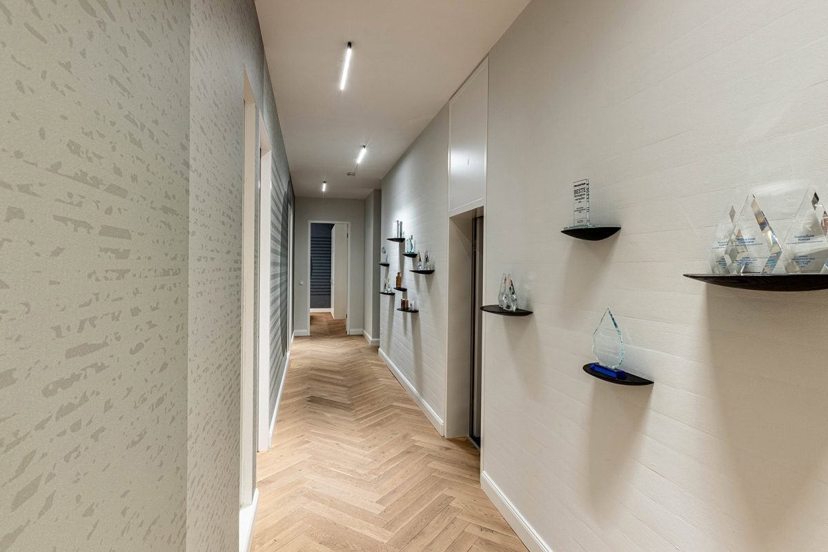 Innenarchitektur München / Innenarchitektur Federleicht - Bürogestaltung, Flur mit grüner Akzentwand und modernen Kreis-Motiven für eine inspirierende Atmosphäre + kleine, schicke Regalbretter für Awards von Mitarbeiter*innen