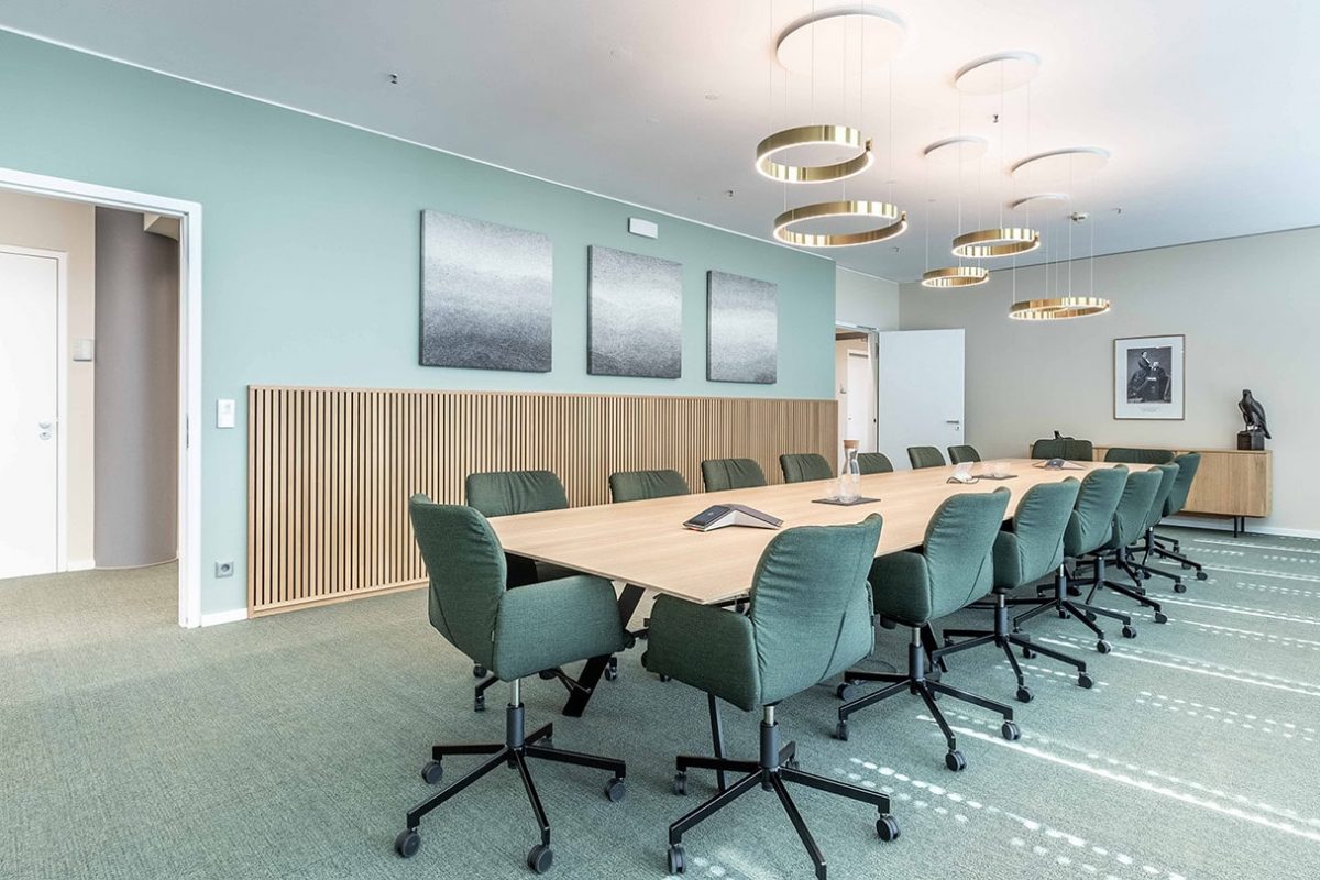 Innenarchitektur München - Bürogestaltung von Innenarchitektur Federleicht aus München, Meetingraum mit großem Meetingtisch aus Holz in der Mitte und grünen, bequemen Meetingstühlen