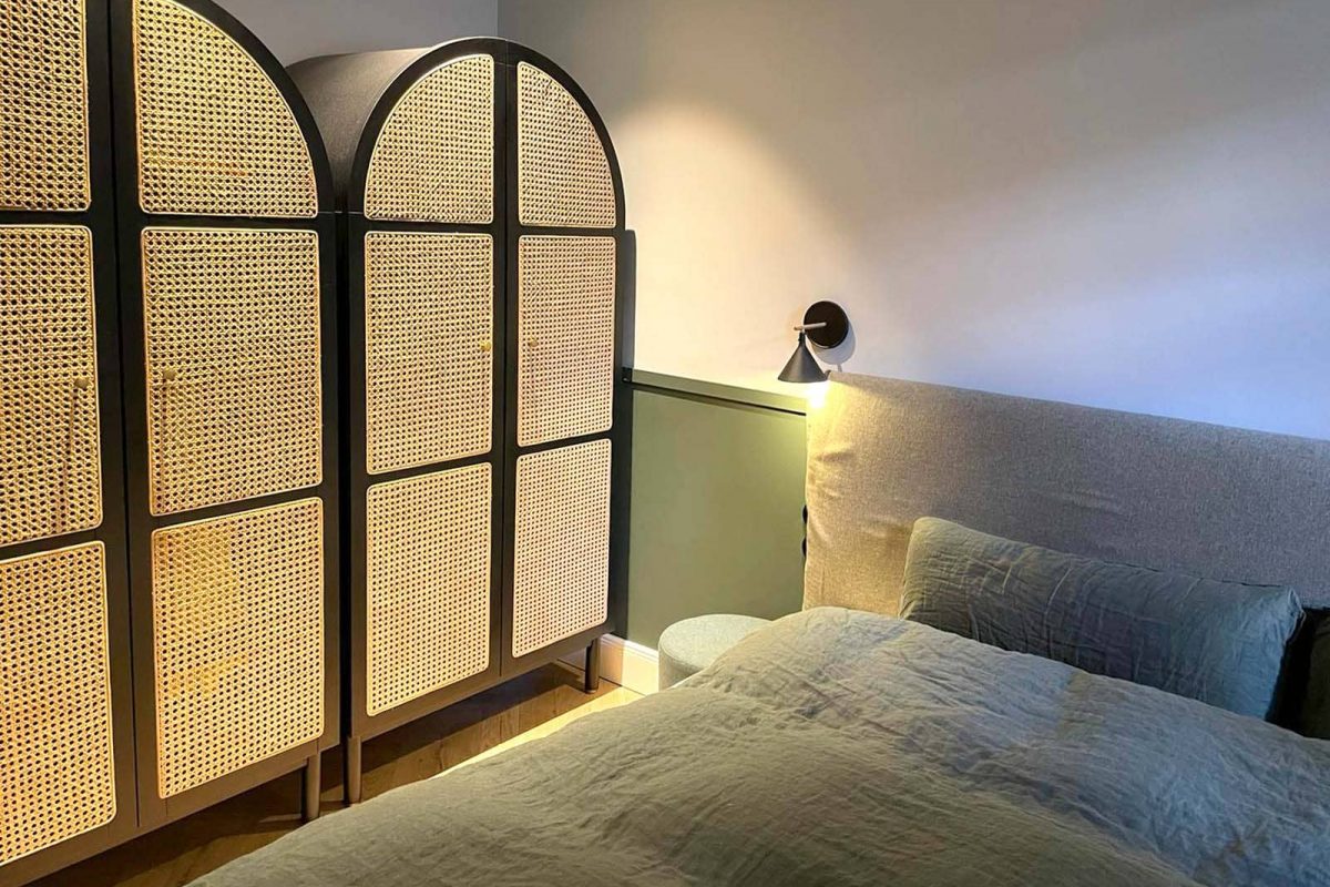 Innenarchitektur München - Schlafzimmer mit runden Rattanschränken und grüner Zierleiste in renovierter Altbauwohnung
